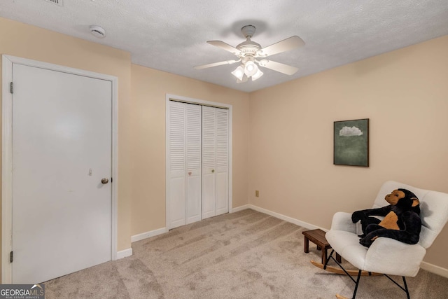 living area featuring carpet floors, a textured ceiling, ceiling fan, and baseboards