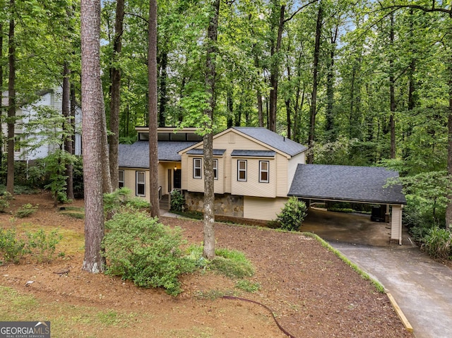 split level home with concrete driveway, a shingled roof, and a carport