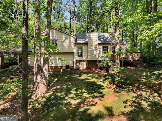 back of property with a deck, a chimney, a shingled roof, a lawn, and stairway