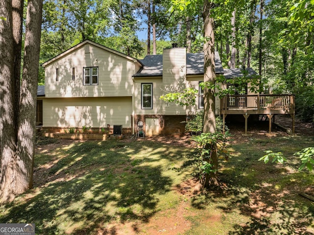 back of house with a shingled roof, a chimney, a yard, and a deck