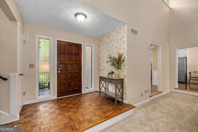 entryway featuring a textured ceiling, baseboards, and visible vents