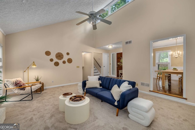 living area featuring visible vents, carpet floors, ceiling fan with notable chandelier, and stairway