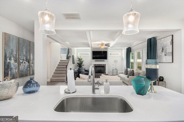 kitchen featuring visible vents, pendant lighting, a fireplace, a sink, and coffered ceiling