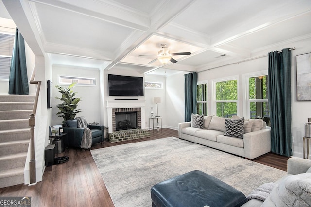 living area featuring a fireplace, beamed ceiling, stairs, and wood finished floors
