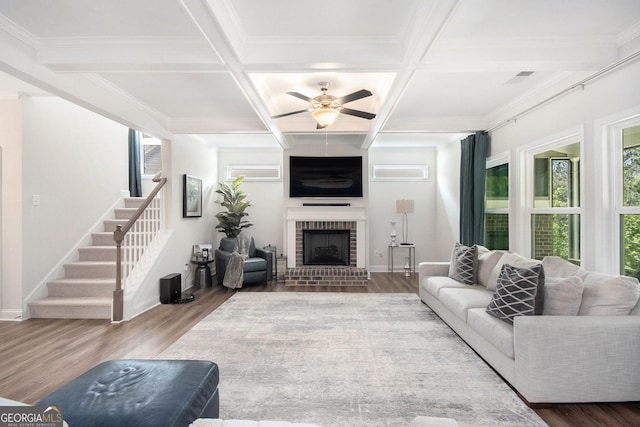 living area featuring ceiling fan, plenty of natural light, wood finished floors, and coffered ceiling