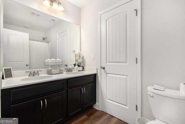 bathroom with toilet, visible vents, a sink, and wood finished floors