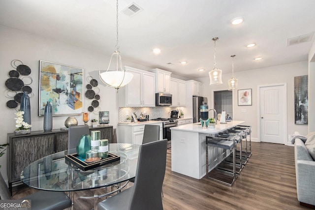 kitchen featuring decorative backsplash, a breakfast bar area, light countertops, white cabinetry, and appliances with stainless steel finishes