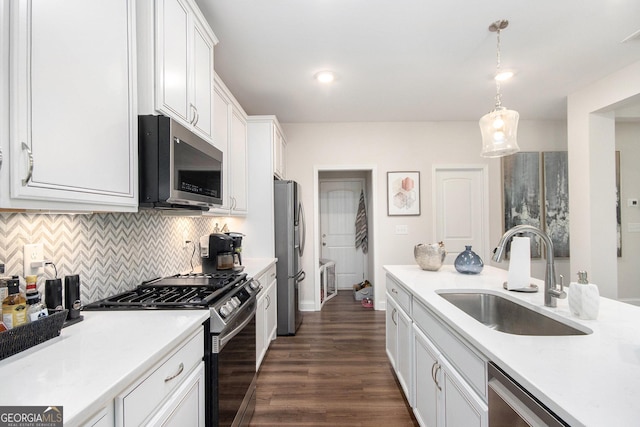 kitchen featuring appliances with stainless steel finishes, a sink, light countertops, white cabinetry, and tasteful backsplash