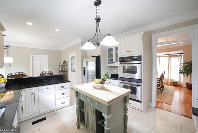 kitchen featuring crown molding, appliances with stainless steel finishes, wood counters, white cabinetry, and light tile patterned floors