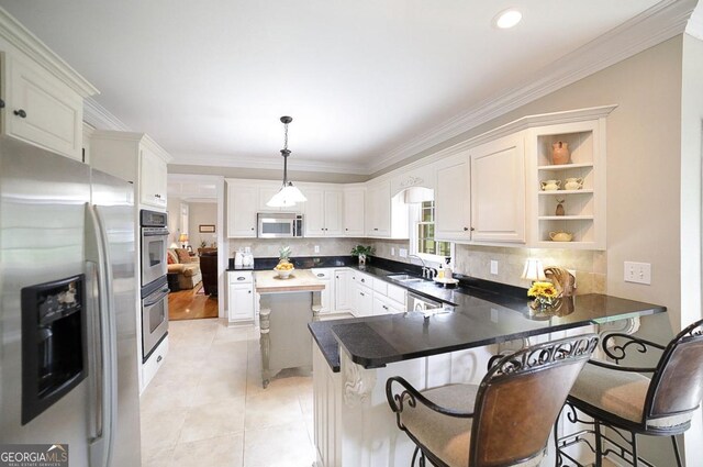 kitchen with a sink, a peninsula, backsplash, and stainless steel appliances