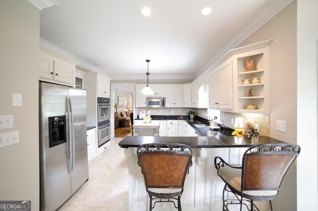kitchen featuring dark countertops, appliances with stainless steel finishes, a sink, a peninsula, and ornamental molding
