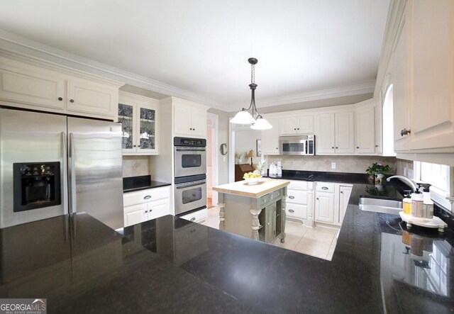 kitchen featuring backsplash, crown molding, appliances with stainless steel finishes, a sink, and white cabinets