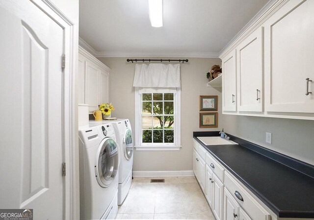 washroom featuring light tile patterned flooring, baseboards, washing machine and clothes dryer, a sink, and cabinet space