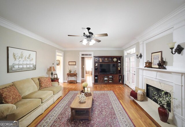 living room featuring crown molding, ceiling fan, wood finished floors, and a fireplace