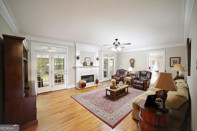 living area with ornamental molding, a ceiling fan, and light wood-style flooring