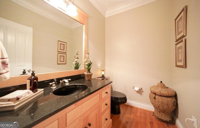 bathroom with vanity, toilet, baseboards, wood finished floors, and ornamental molding
