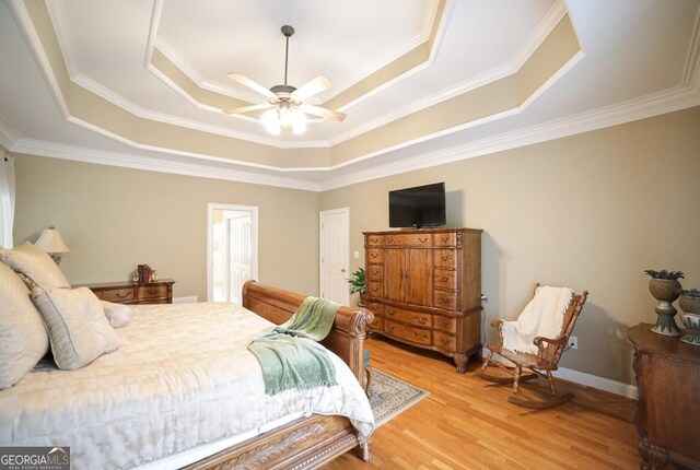 bedroom with ornamental molding, light wood-style flooring, and a raised ceiling