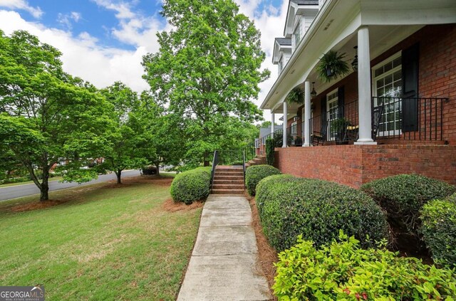 view of yard with covered porch and stairway