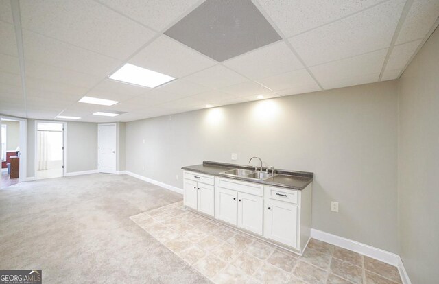 interior space with baseboards, a sink, and a drop ceiling