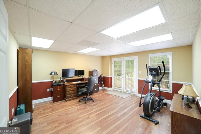 office space with baseboards, light wood-style flooring, and a paneled ceiling