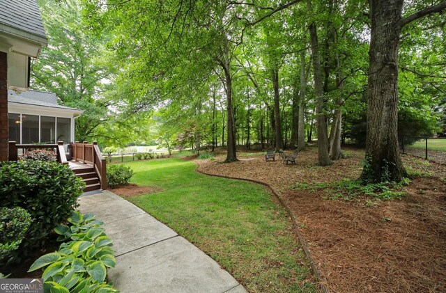 view of yard with a deck, fence, and a sunroom
