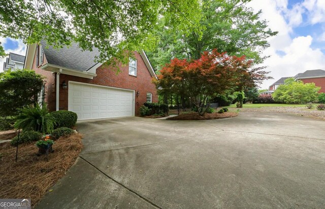 view of front of property with concrete driveway, brick siding, a shingled roof, and a garage