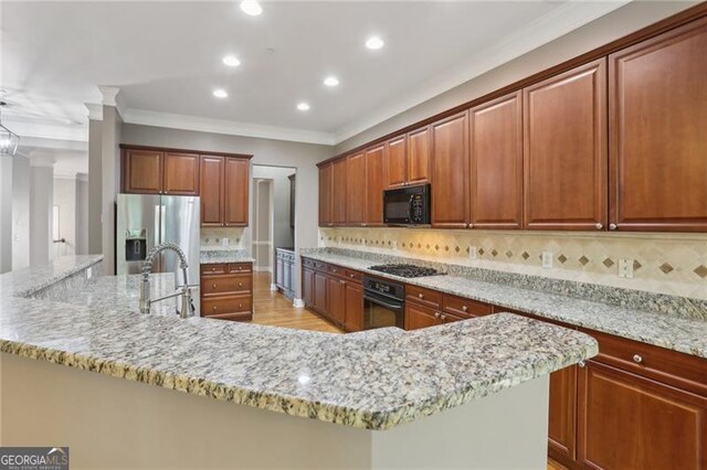 kitchen with crown molding, light stone countertops, a sink, backsplash, and black appliances