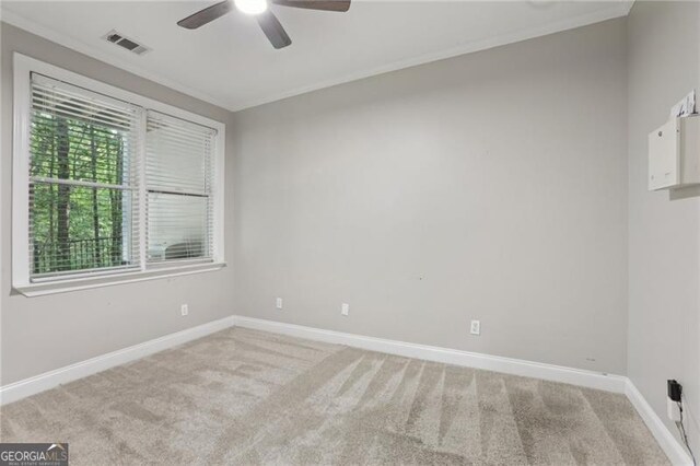 unfurnished room with crown molding, a ceiling fan, light colored carpet, and visible vents