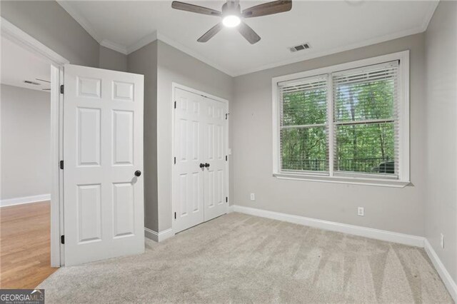 unfurnished bedroom featuring baseboards, ornamental molding, carpet floors, and visible vents