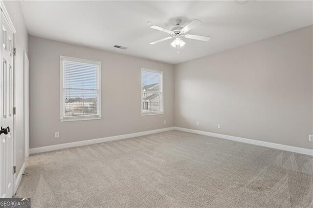 unfurnished room featuring baseboards, a ceiling fan, light colored carpet, and visible vents