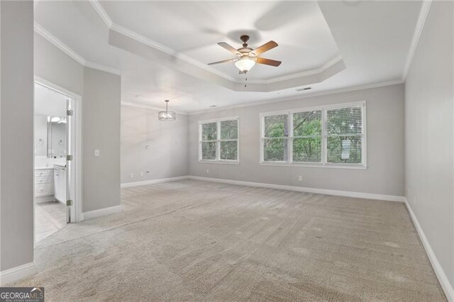 interior space featuring light colored carpet, crown molding, a raised ceiling, and ceiling fan with notable chandelier