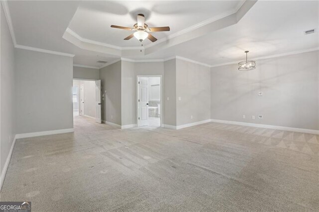 carpeted empty room featuring ceiling fan with notable chandelier, crown molding, a tray ceiling, and visible vents