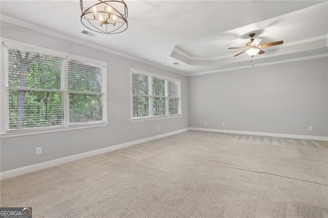 empty room with plenty of natural light, ornamental molding, a raised ceiling, and carpet
