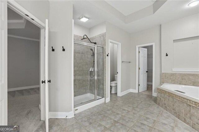full bath featuring baseboards, a garden tub, a stall shower, and toilet
