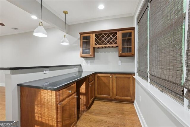 bar with crown molding, hanging light fixtures, light wood finished floors, and wet bar