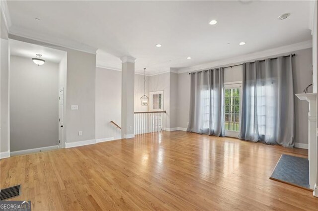 unfurnished living room with visible vents, ornamental molding, and wood finished floors