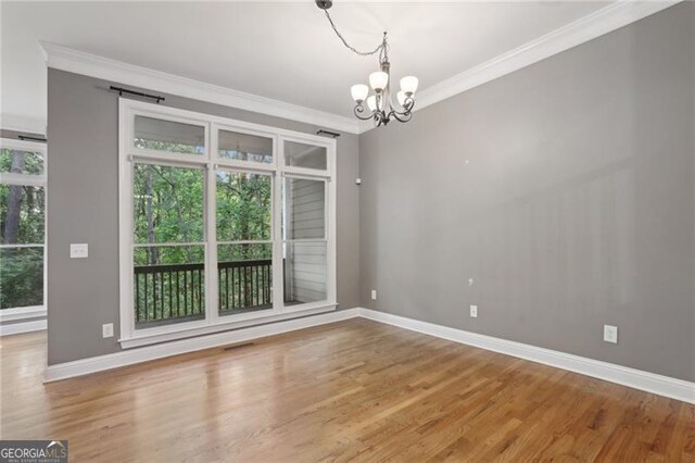 unfurnished dining area featuring crown molding, baseboards, an inviting chandelier, and wood finished floors
