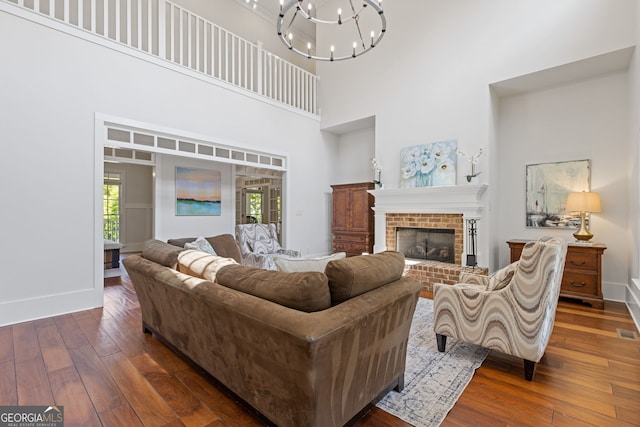 living area featuring an inviting chandelier, baseboards, hardwood / wood-style flooring, and a towering ceiling