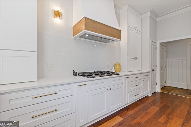 kitchen with stainless steel gas cooktop, light countertops, white cabinets, custom exhaust hood, and dark wood-type flooring