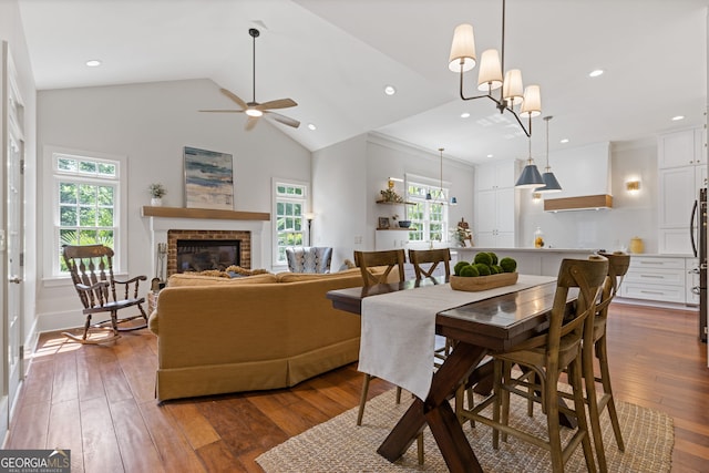 dining space featuring a ceiling fan, plenty of natural light, wood-type flooring, and a brick fireplace