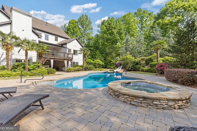 pool with a patio, an in ground hot tub, and a wooden deck