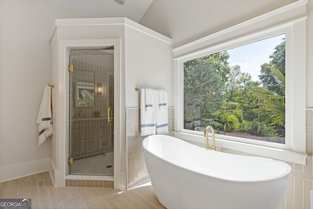 full bath with a freestanding bath, tile walls, a shower stall, and a wealth of natural light