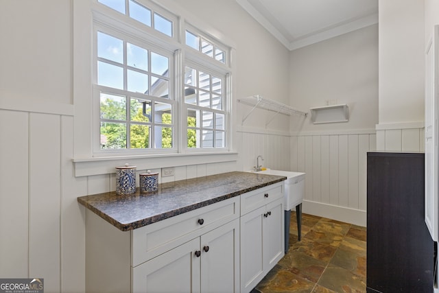 interior space featuring crown molding, a wainscoted wall, stone finish floor, and a decorative wall