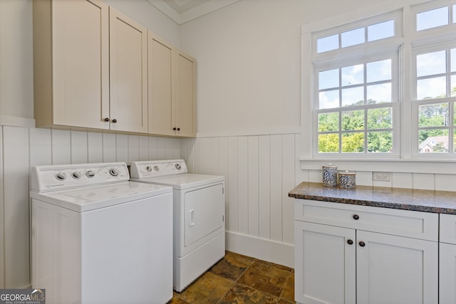 laundry room featuring cabinet space, washing machine and dryer, stone finish floor, and a wainscoted wall
