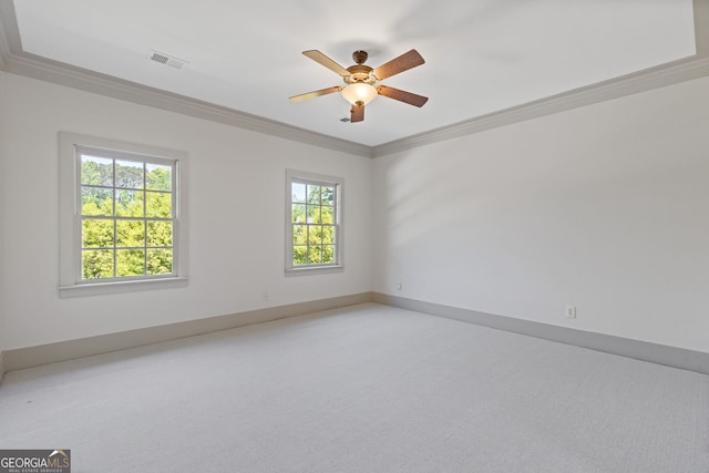 spare room with ceiling fan, visible vents, crown molding, light colored carpet, and baseboards