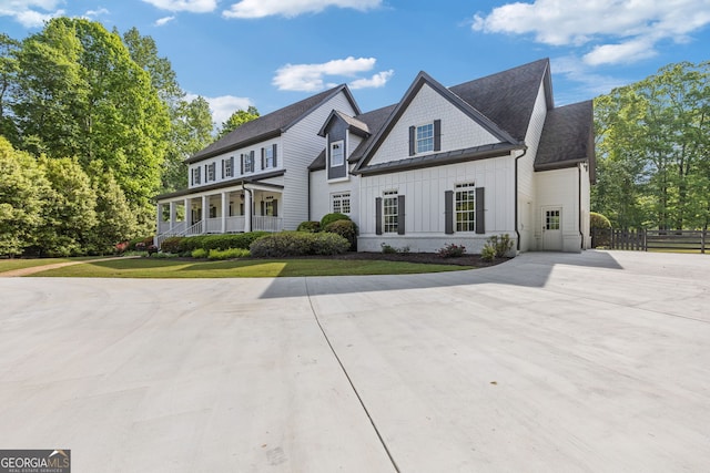 view of front of house with a front lawn, board and batten siding, fence, and concrete driveway