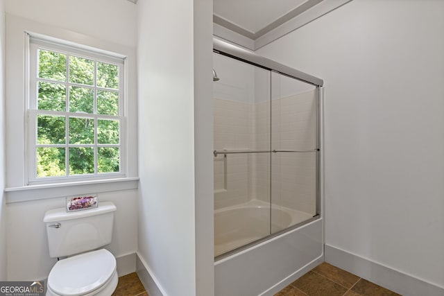 full bath featuring baseboards, a healthy amount of sunlight, shower / bath combination with glass door, and toilet