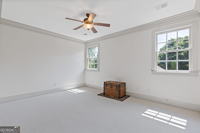 empty room with crown molding, carpet, a ceiling fan, and visible vents
