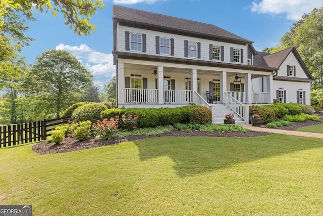 colonial inspired home featuring fence, covered porch, ceiling fan, and a front yard