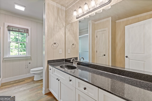 bathroom with crown molding, vanity, toilet, baseboards, and wood finished floors
